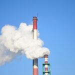 A picture of a red and black smoke stack emitting harmful explosive gas into the air